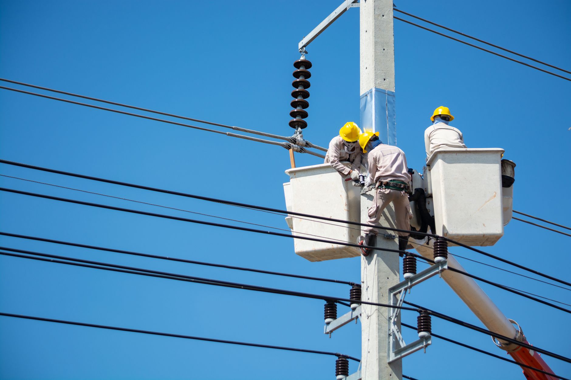 Electricians in safety gear working methodically on power installation work